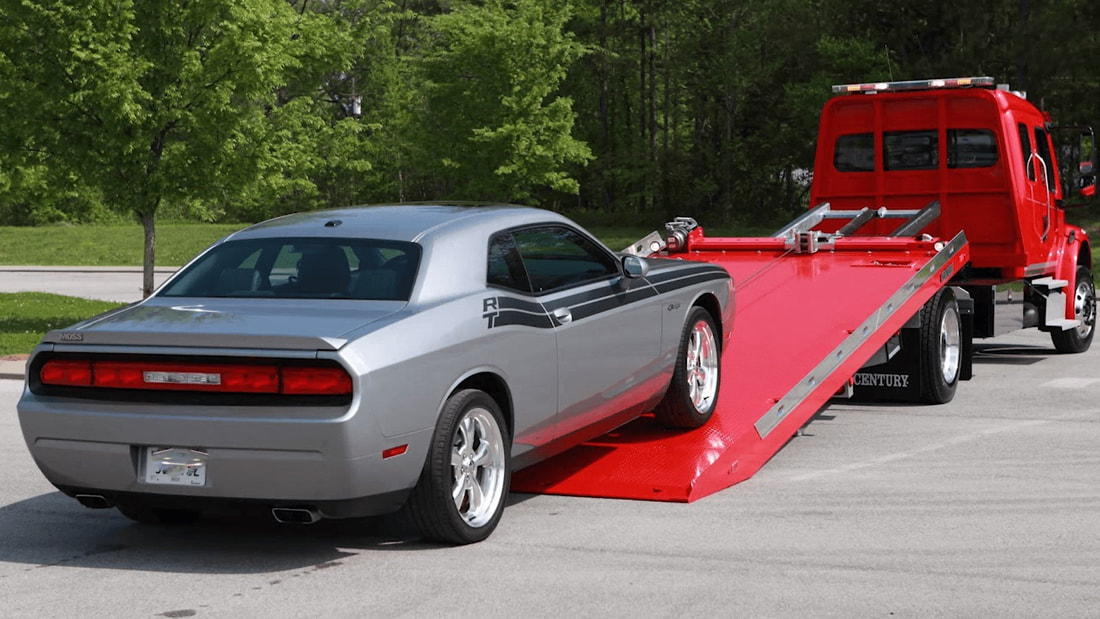 Silver Dodge Challenger on red flatbed tow truck